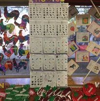 Colorful classroom display features rooster art, educational posters, and a central board with visual aids and cutouts, creating a vibrant learning environment.