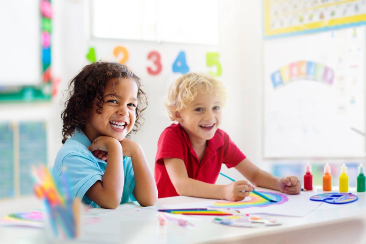 Kids go back to school. Interracial group of children of mixed age in classroom. Students learn to read and write. Preschooler or kindergarten kid with teacher. Child learning letters with flash cards